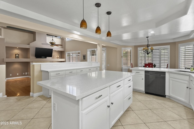 kitchen with dishwasher, a center island, a raised ceiling, ceiling fan with notable chandelier, and light tile patterned floors