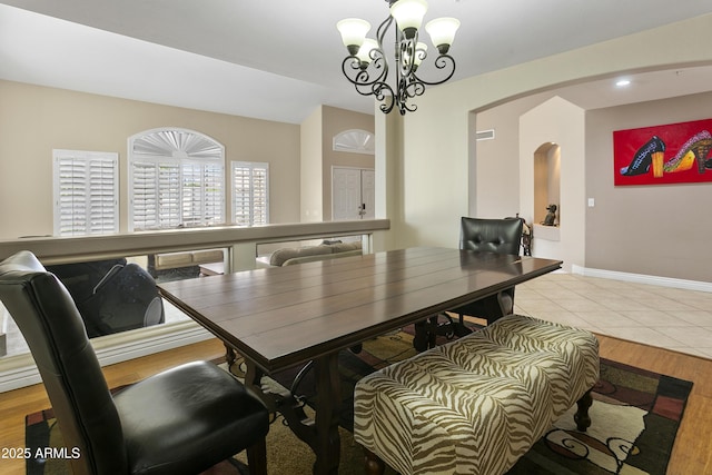 dining room with an inviting chandelier, arched walkways, light wood-style flooring, recessed lighting, and baseboards