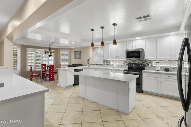 kitchen featuring visible vents, a peninsula, light countertops, a sink, and black appliances