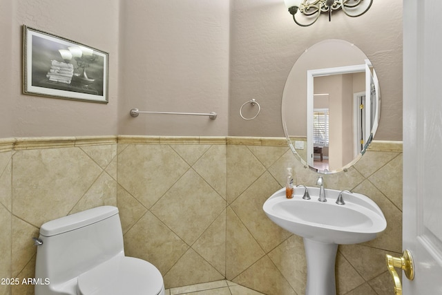 half bathroom featuring tile walls, wainscoting, and toilet
