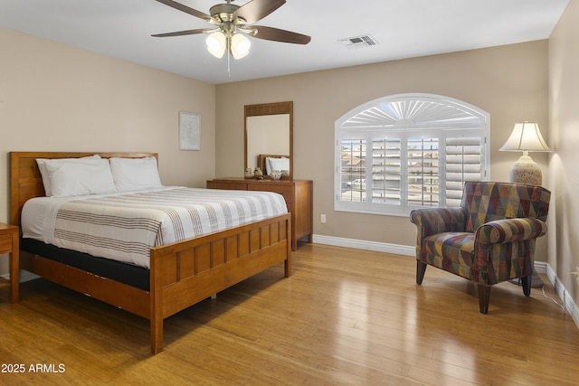 bedroom featuring light wood-style floors, baseboards, ceiling fan, and visible vents