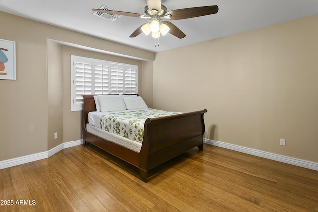 bedroom with baseboards, ceiling fan, wood finished floors, and visible vents
