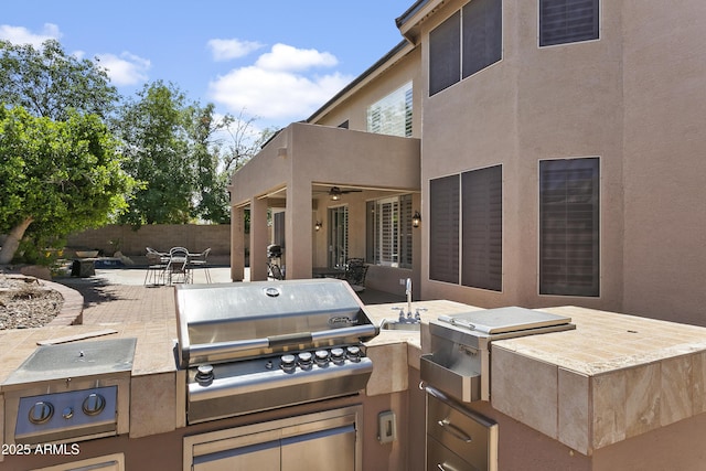 view of patio featuring an outdoor kitchen, fence, a ceiling fan, and a grill