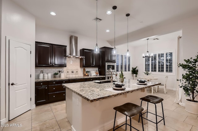 13145 W Whisper Rock Trl, Peoria, AZ 85383 - kitchen featuring exhaust hood, a breakfast bar area, tasteful backsplash, stainless steel microwave, and an island with sink