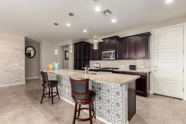 kitchen featuring pendant lighting, stainless steel appliances, a kitchen breakfast bar, and sink