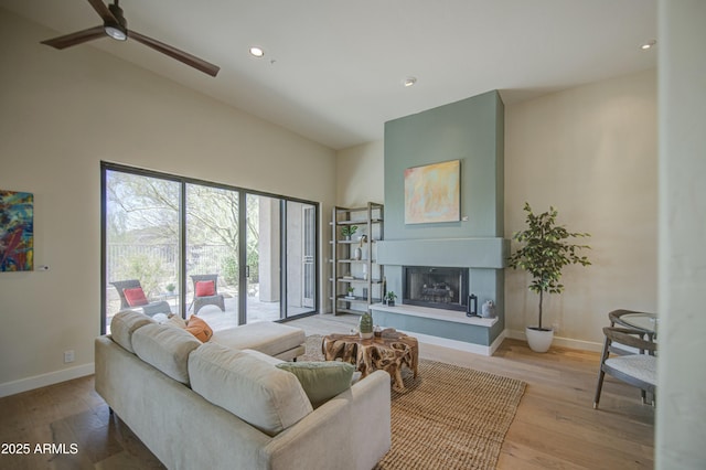 living area with baseboards, a fireplace with raised hearth, and light wood-style floors