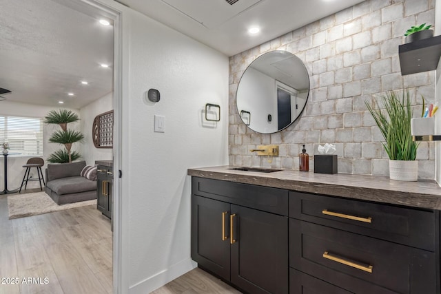 bathroom with wood finished floors, baseboards, vanity, and recessed lighting