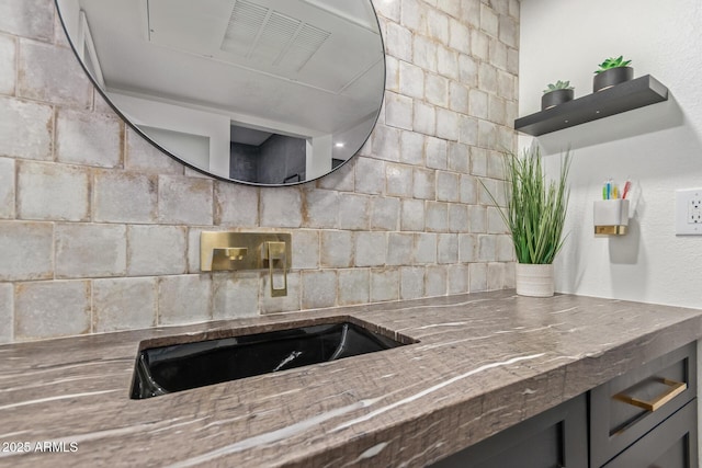 kitchen featuring a sink, stone counters, and open shelves