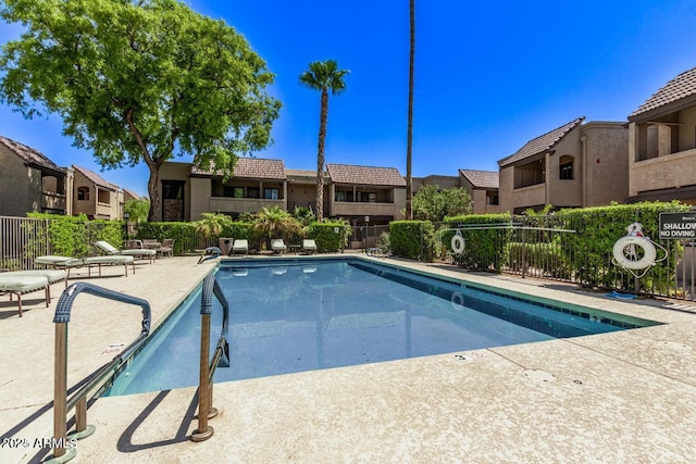 community pool featuring a residential view, a patio area, and fence