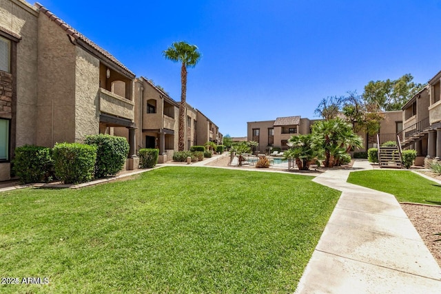 view of home's community with a pool, a lawn, a residential view, and stairs