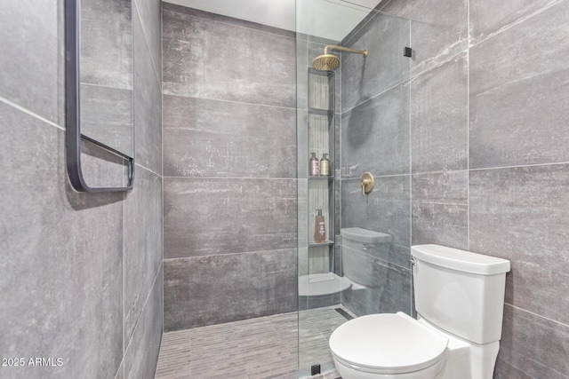 full bath with tiled shower, toilet, and tile walls