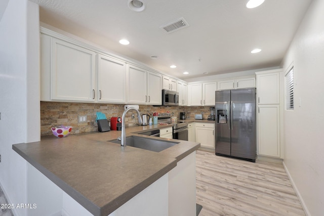 kitchen with stainless steel appliances, kitchen peninsula, sink, and white cabinets