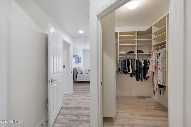 walk in closet with light hardwood / wood-style floors