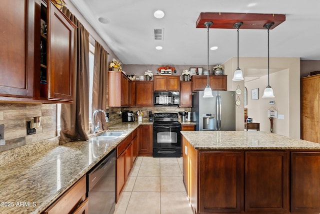 kitchen featuring light stone counters, hanging light fixtures, black appliances, and sink