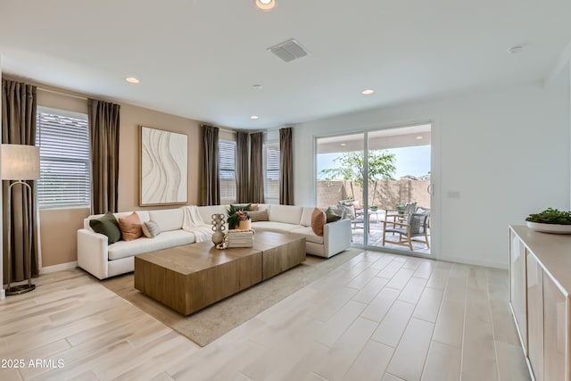 living room featuring light wood-style floors, recessed lighting, visible vents, and baseboards