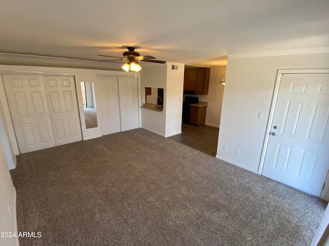 unfurnished living room with ceiling fan and dark colored carpet