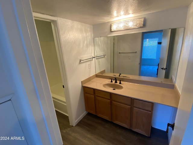 bathroom with hardwood / wood-style flooring, vanity, shower / bathtub combination, and a textured ceiling