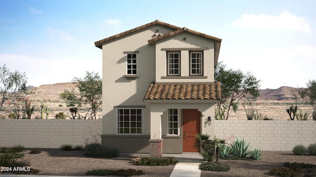 mediterranean / spanish-style home featuring a fenced front yard, a tile roof, a mountain view, and stucco siding