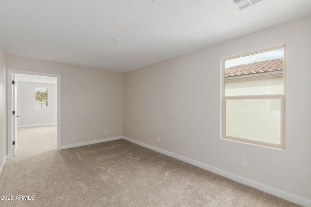 spare room with light colored carpet, visible vents, and baseboards