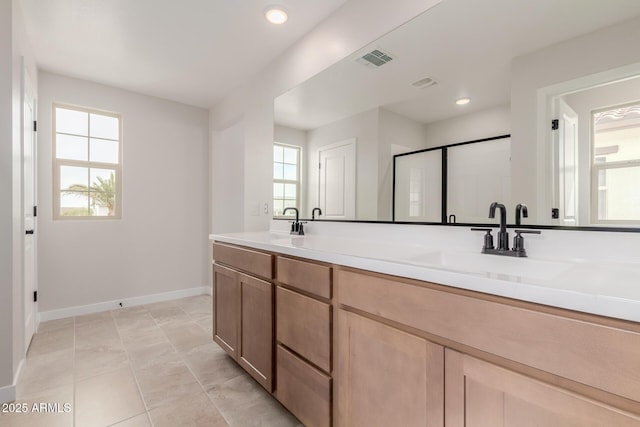 bathroom featuring double vanity, visible vents, a stall shower, a sink, and baseboards