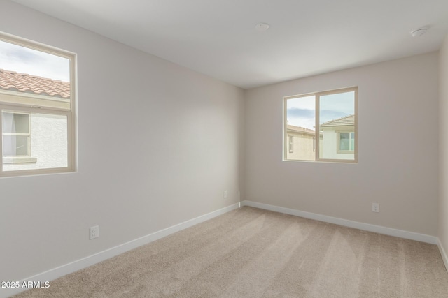 unfurnished room featuring light colored carpet and baseboards