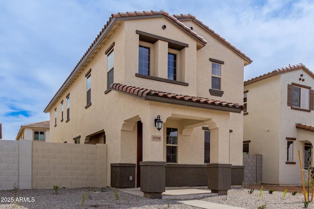 view of front of home with a tiled roof, fence, and stucco siding