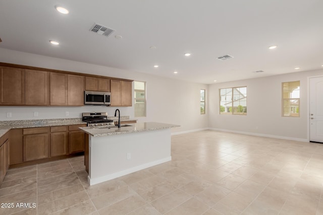 kitchen featuring appliances with stainless steel finishes, a sink, visible vents, and light stone countertops