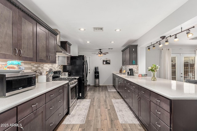 kitchen featuring dark brown cabinetry, visible vents, appliances with stainless steel finishes, a peninsula, and a sink