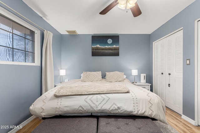 bedroom featuring a closet, wood finished floors, a ceiling fan, and baseboards