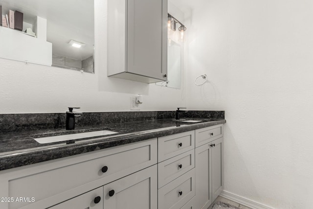 full bath with double vanity, baseboards, and a sink