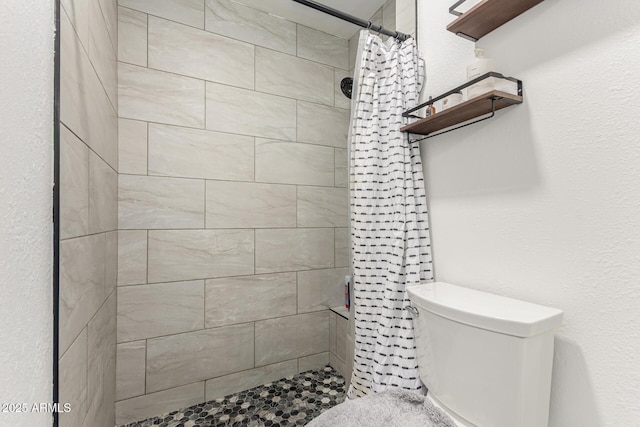 full bathroom featuring toilet and tiled shower