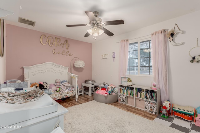 bedroom with a ceiling fan, visible vents, and wood finished floors