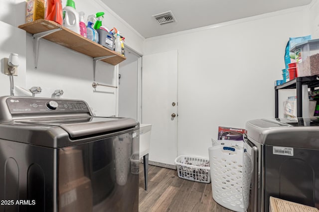 laundry room with visible vents, ornamental molding, wood finished floors, laundry area, and independent washer and dryer