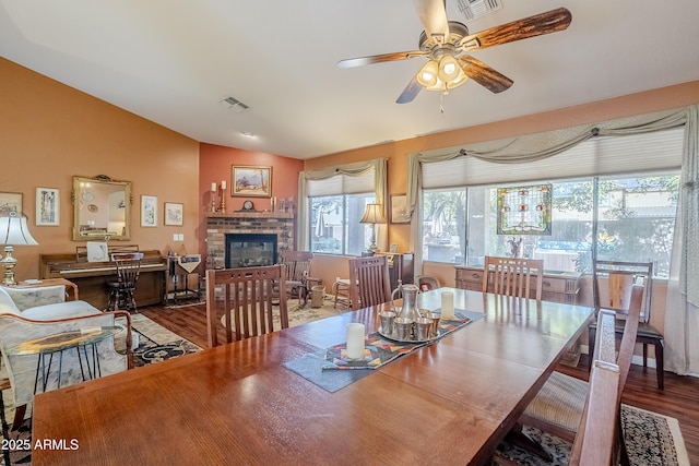 dining area with ceiling fan, lofted ceiling, a fireplace, and hardwood / wood-style flooring