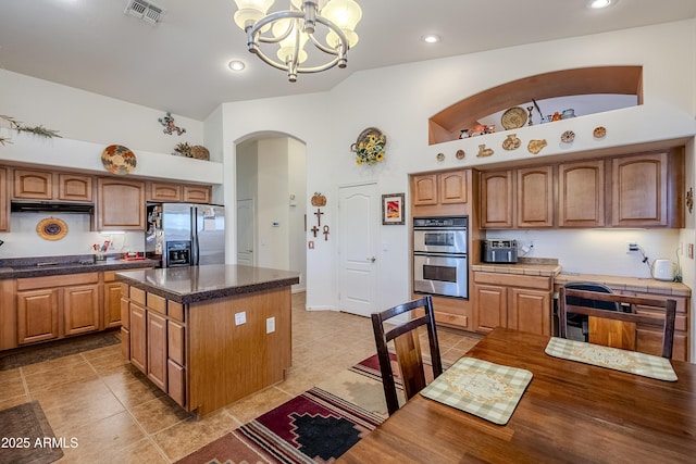 kitchen featuring a chandelier, appliances with stainless steel finishes, pendant lighting, high vaulted ceiling, and a kitchen island