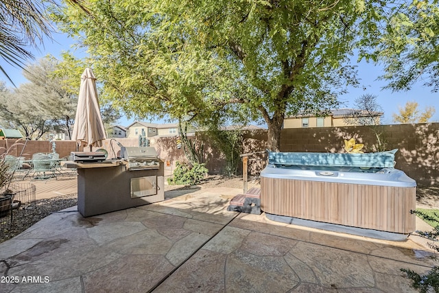 view of patio with a hot tub, exterior kitchen, and grilling area