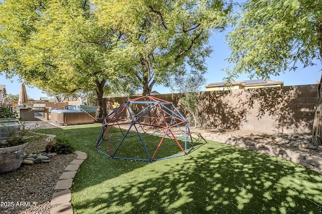 view of playground with a lawn and a hot tub