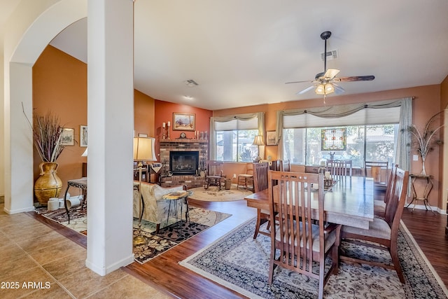 dining space with lofted ceiling, hardwood / wood-style floors, a fireplace, and ceiling fan