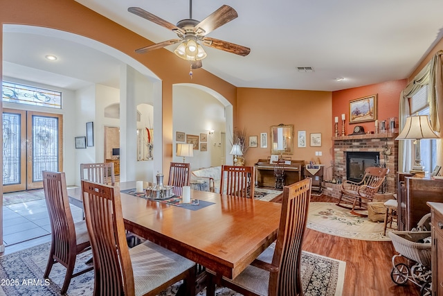 dining space featuring ceiling fan, light wood-type flooring, and a fireplace