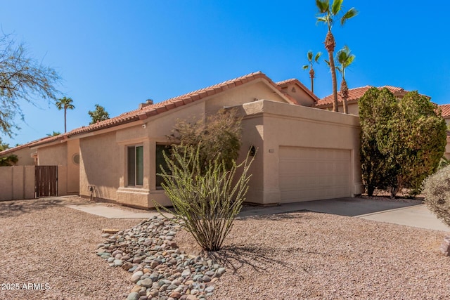 mediterranean / spanish-style house with stucco siding, concrete driveway, an attached garage, and fence