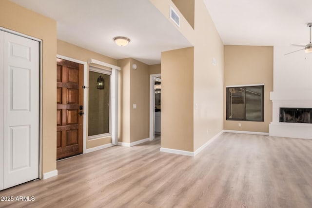 unfurnished living room featuring a ceiling fan, visible vents, baseboards, a fireplace, and light wood-style floors