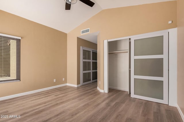 unfurnished bedroom with visible vents, baseboards, vaulted ceiling, wood finished floors, and a ceiling fan