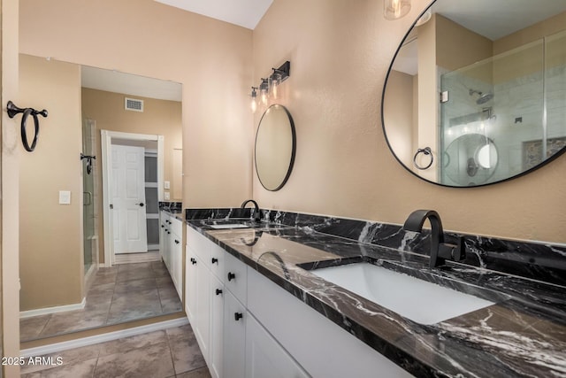 bathroom with a shower stall, double vanity, and a sink