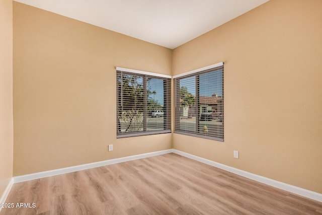 spare room featuring baseboards and wood finished floors