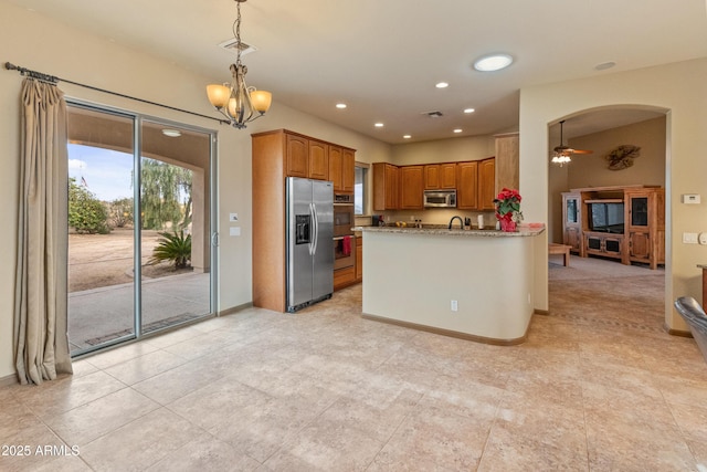 kitchen featuring decorative light fixtures, kitchen peninsula, stainless steel appliances, light stone countertops, and ceiling fan with notable chandelier