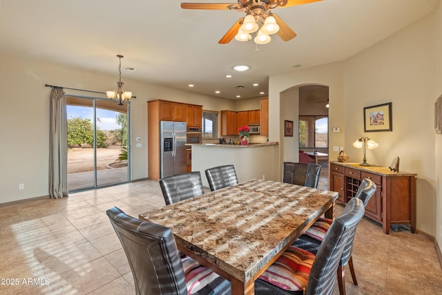 tiled dining area featuring ceiling fan with notable chandelier