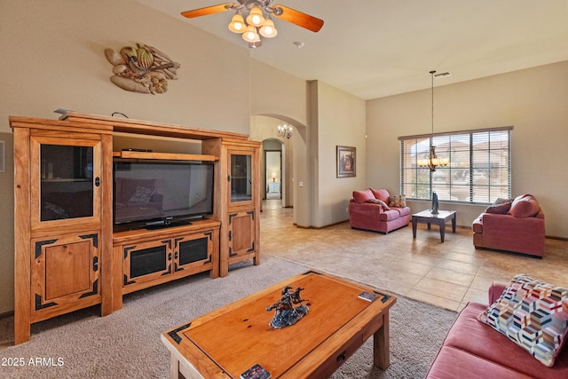 living room featuring a high ceiling, light tile patterned flooring, and ceiling fan with notable chandelier