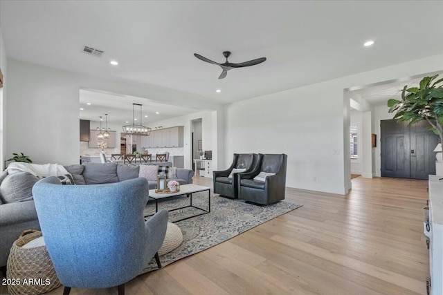 living area with ceiling fan, light wood-type flooring, recessed lighting, and a chandelier