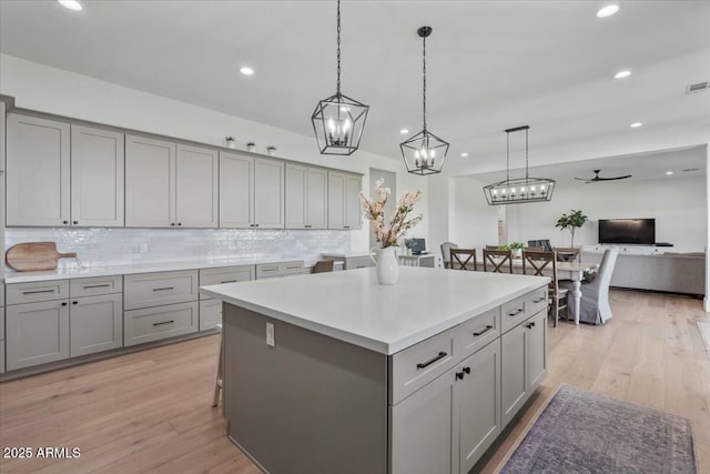 kitchen with gray cabinetry, light wood finished floors, tasteful backsplash, and recessed lighting