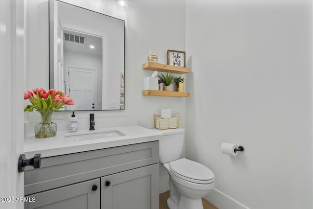 half bathroom featuring vanity, toilet, and baseboards